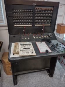 An antique brown telephone switchboard and headset located in the Wheeling Historical Museum.